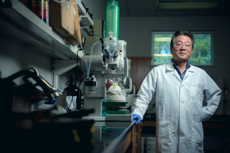 a researcher in a lab coat leaning against a lab bench