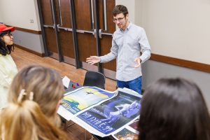 Researcher showing students illustrated poster prints