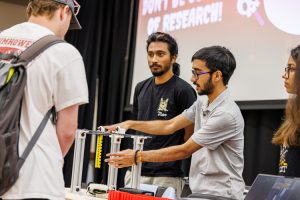 graduate student researchers demonstrating scientific equipment